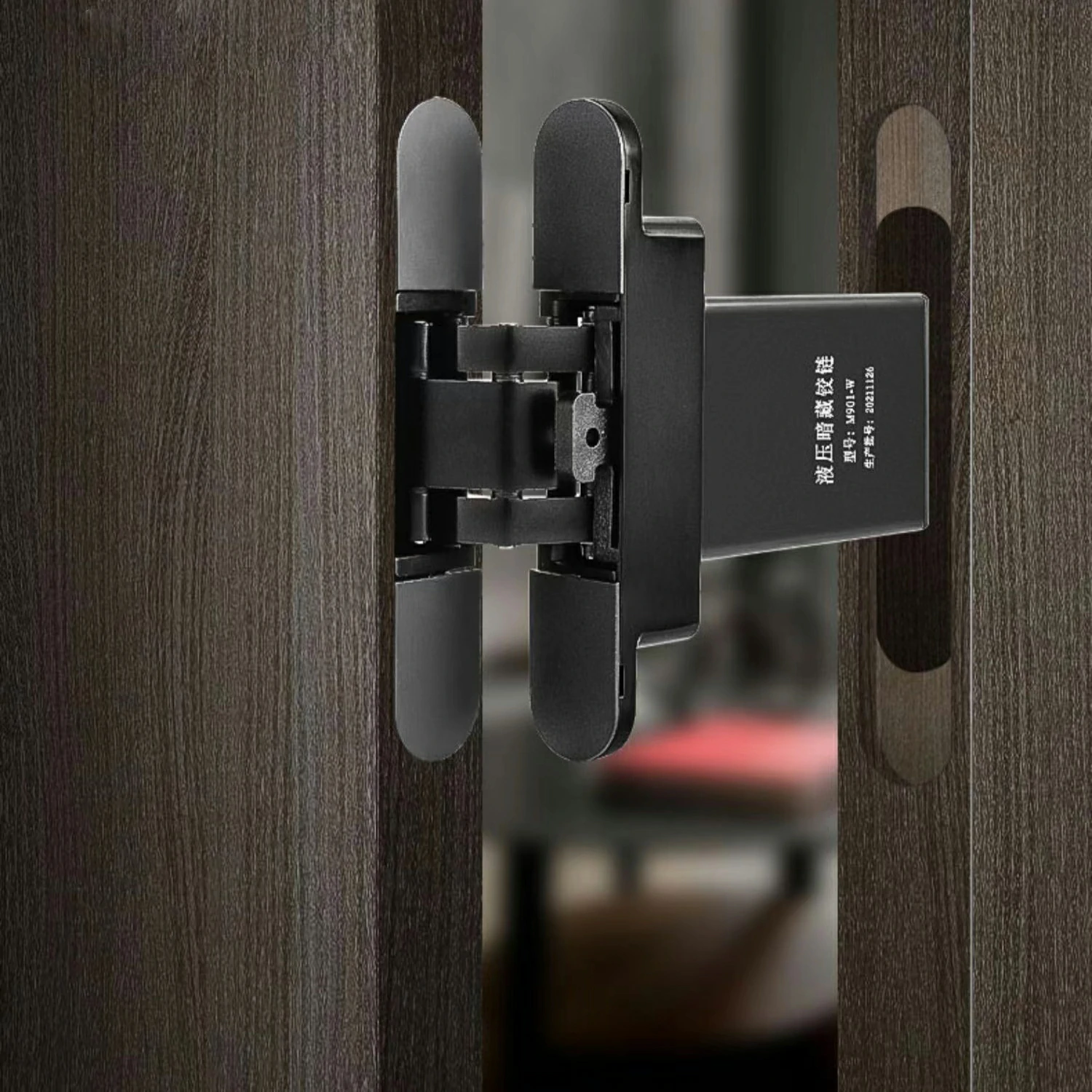 Installed invisible hydraulic door hinge (Model M901-W) showing flush fit on dark wood door.