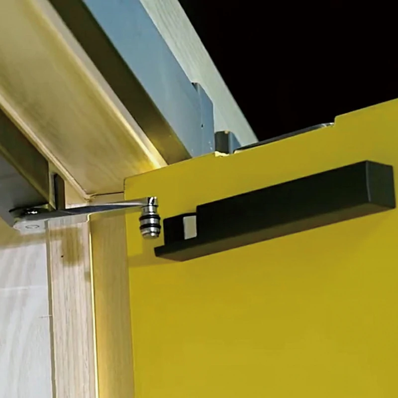 Top-mounted hydraulic door damper installed on a wooden door frame to prevent slamming.