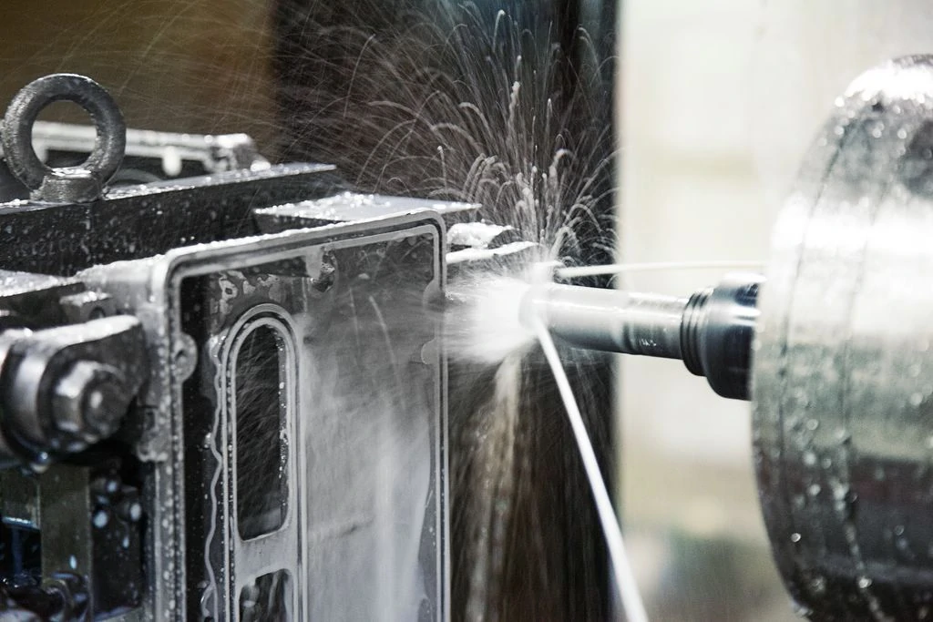 CNC drilling machine cutting a metal workpiece with coolant spraying for cooling and lubrication