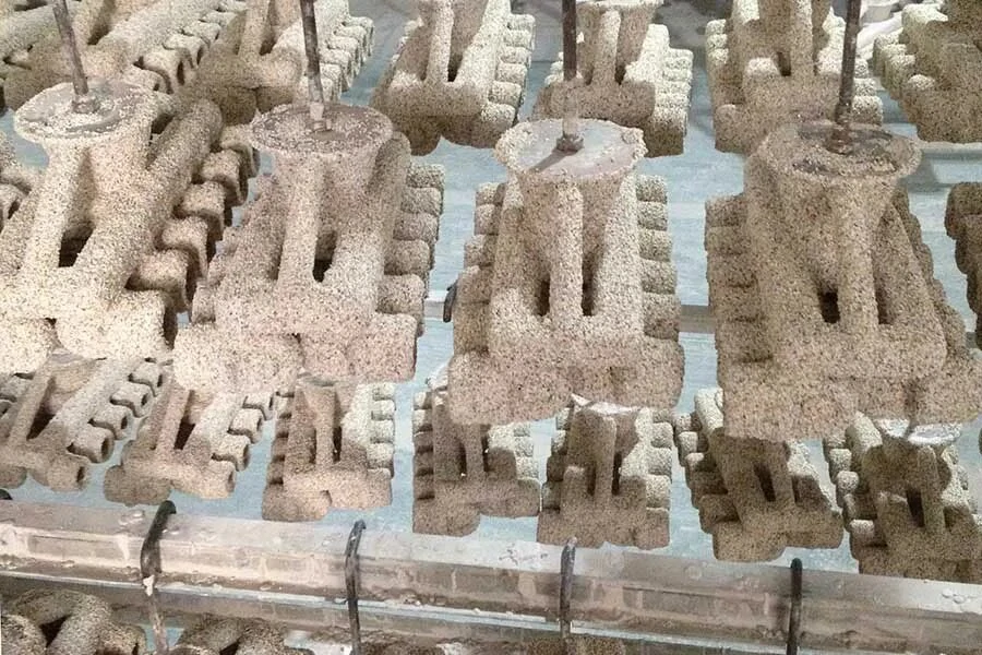 Investment casting shells arranged for hardening in preparation for precision casting, with intricate designs visible.
