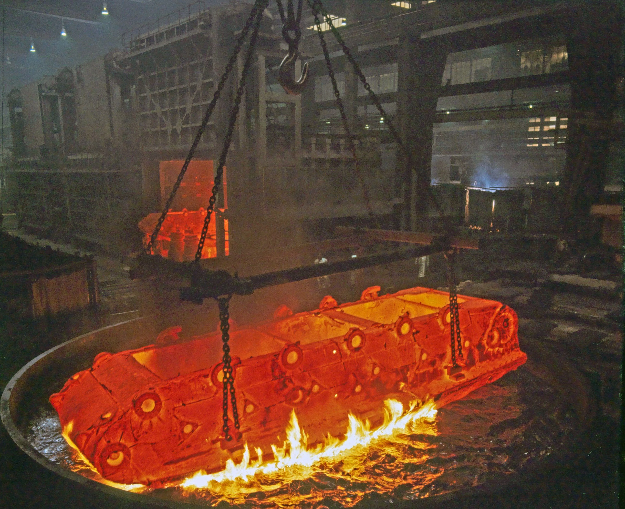 Procédé de coulée de métal en fusion dans une fonderie industrielle, montrant une chaleur intense et du métal en fusion coulé dans des moules.