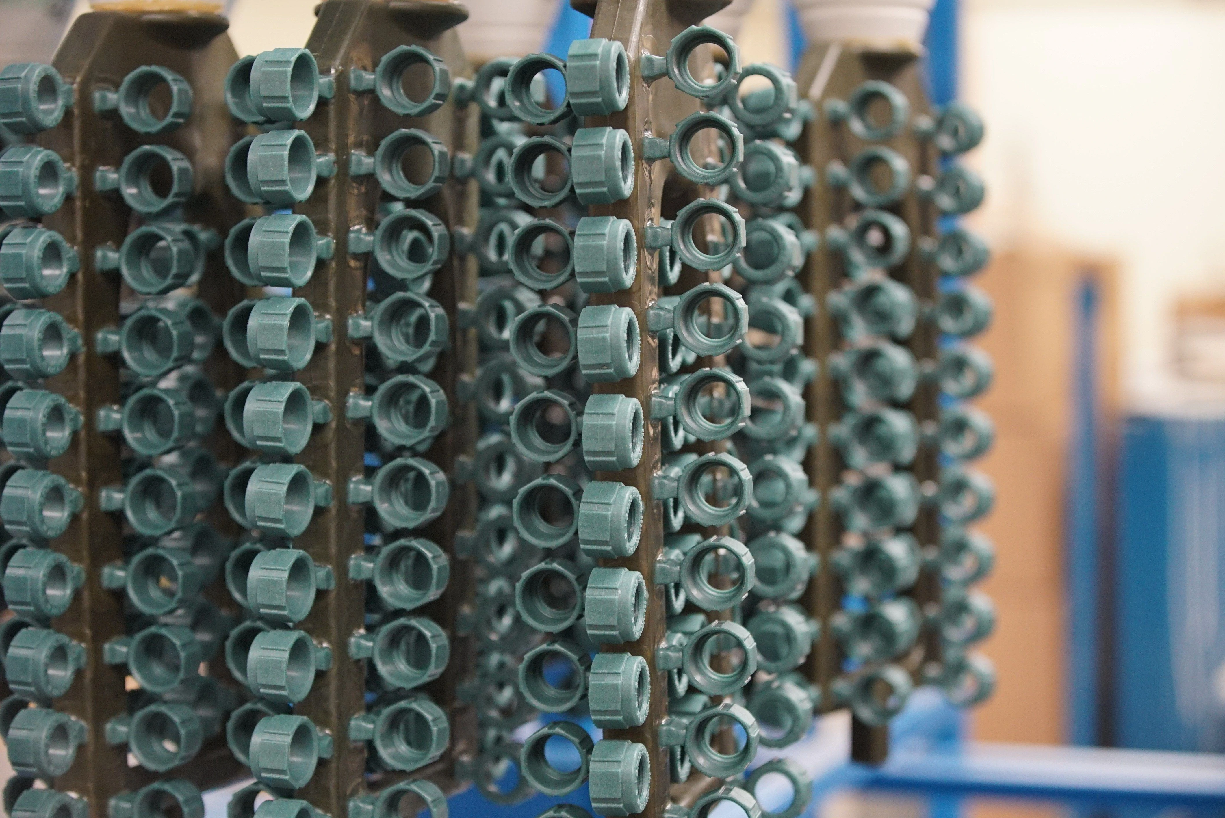 Rows of plastic molded components hanging for drying or further processing in a manufacturing facility.