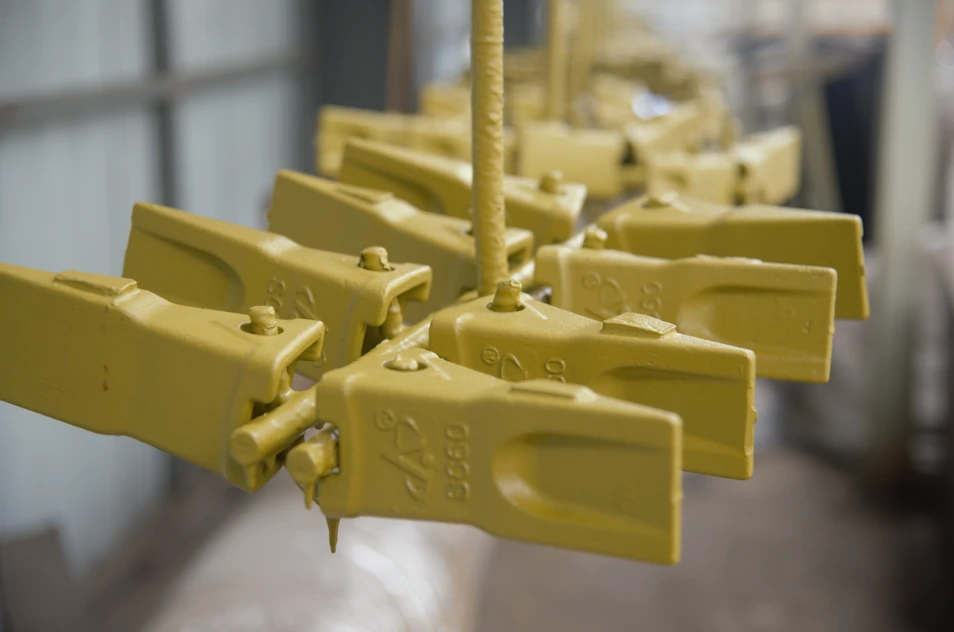 Freshly painted yellow castings hanging on production line after surface coating for corrosion protection and improved appearance.