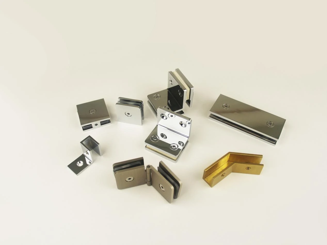 Assorted stainless steel and brass glass hinges and clamps in various designs, showcasing OEM customization options for frameless shower door hardware.