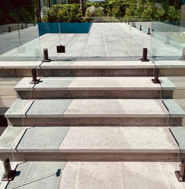 Modern frameless glass pool fencing system with stainless steel spigots